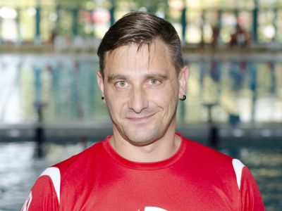 Trainer Holger Konzack im roten T-Shirt. Im Hintergrund ein Schwimmbecken.